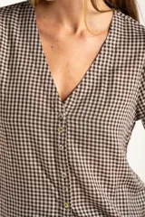Blusa de algodón con estampado de cuadros vichy en tonos negro y blanco. Presenta escote en V, cierre frontal con botones y mangas cortas abullonadas con terminación elástica.