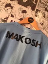 Remera celeste con estampado de un monstruo de nieve blanco y el logo de la serie Sk8: The Infinity.