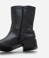 Bota de caña corta color negro, de PU (cuero sintético), con taco bloque bajo, punta levemente redondeada y dos tiras con hebillas metálicas en el lateral.