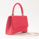 Cartera de mano tipo sobre color rojo, con acabado aterciopelado, asa superior rígida y cadena metálica dorada extraíble.