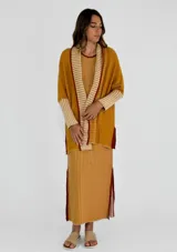 Vestido midi de punto con diseño a rayas verticales en tonos mostaza y blanco, con cuello redondo y sisas contrastadas en color bordó. Presenta aberturas laterales en el ruedo con detalles en color bordó.