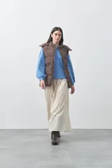 Chaleco puffer negro con diseño acolchado, capucha desmontable y cierre frontal. Cuenta con cordones ajustables en la cintura y bolsillos laterales.