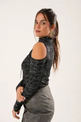 Polera negra con lurex, cuello alto, mangas largas y aberturas en hombros y pecho.