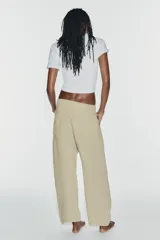 Jeans de tiro medio y corte barrel con diseño de perneras curvadas, tiro medio, trabillas para cinturón y cinco bolsillos. Presenta lavado clásico y costuras pespunteadas decorativas en la parte delantera.