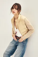 Campera puffer color beige con cuerpo acolchado y mangas tejidas de punto. Presenta cuello alto, cierre frontal y bolsillos laterales.