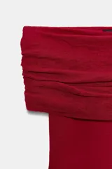 Top de punto color crema, con escote recto y hombros descubiertos, manga larga y diseño ajustado.