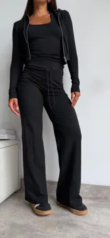 Conjunto de dos piezas color marrón chocolate, compuesto por una campera ajustada de manga larga con cierre frontal y un pantalón de corte recto con cintura elástica y cordón ajustable.