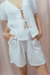 Short blanco de calce relajado con cintura elástica y lazo regulable. Presenta bolsillos amplios con ribete interior de color naranja neón.
