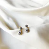 Aros pequeños con forma de gota colgante hechos en zirconia sobre base de metal plateado.