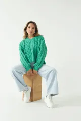 Sweater verde esmeralda de punto con diseño trenzado y textura en relieve, fit amplio y cómodo, con hombros caídos y cuello redondo.