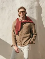 Campera de lino color marrón claro, de corte recto con cierre frontal de cremallera, cuello clásico y dos bolsillos frontales con solapa en el pecho.