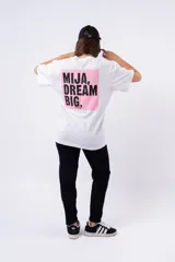 Remera negra de corte oversize con estampado frontal que dice "MIJA DREAM BIG" en tipografía blanca y rosa.