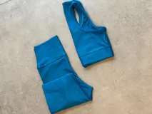 Conjunto deportivo azul con textura acanalada, compuesto por calzas largas de tiro alto y top deportivo con breteles anchos.