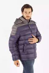 Campera puffer de diseño color block, combinando tonos azul oscuro y gris. Cuenta con capucha desmontable, cierre frontal de cremallera, cuello elevado y bolsillos laterales con cierre de botón.