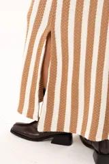 Falda larga tejida a rayas verticales color beige y blanco, con pretina elástica y tajos laterales.