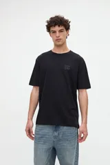 Remera de manga corta color beige, confeccionada en jersey de algodón con textura suave y calce relaxed. Presenta costuras a contratono en la espalda y un diseño estampado en la parte posterior con ilustraciones de estilo lineal y frases manuscritas.