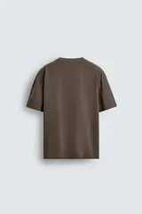 Camiseta de corte relajado confeccionada en algodón con textura irregular, cuello redondo y manga corta.