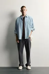 Camisa regular fit de denim de algodón con efecto lavado, cuello solapa y manga larga con puño abotonado. Tiene un bolsillo de parche en el pecho con detalle bordado a contraste y cierre frontal con botonadura.