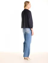 Blusa de gasa con plisado soleil, cuello a la base fruncido con escote en V regulable mediante lazos, y mangas largas abullonadas con puños sastreros.