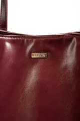 Bolso tipo tote de gran tamaño en color bordó con acabado brillante. Cuenta con doble asa de hombro y placa metálica decorativa con logo en la parte frontal.