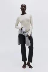 Top de manga larga confeccionado en punto de crepé, con cuello redondo y diseño de peplum. Presenta costuras moldeadoras tanto en el frente como en la espalda.