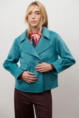 Chaqueta de paño color gris oscuro, con solapas amplias y cierre frontal mediante un alamar único. Presenta bolsillos laterales y mangas largas con puños rectos.