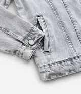 Campera de jean de hombre, color celeste claro con efecto desteñido y desgastado. Presenta cuello, manga larga, cierre frontal con botones blancos y dos bolsillos con solapa y botón en el pecho.