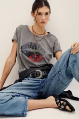 Remera de algodón gris con efecto acid wash, mangas cortas y estampa frontal de labios oscuros con la palabra "Kiss" en rojo.