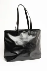Bolso tipo tote bag color marrón, confeccionado en cuero sintético, con doble asa superior y detalle de placa metálica dorada con logo en la parte frontal.