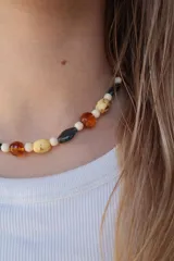 Collar corto con cuentas de cristal y resina en tonos blanco, ámbar, amarillo moteado y gris oscuro.