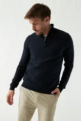 Sweater gris de punto con cuello alto y medio cierre con cremallera. Tiene puños acanalados y logo bordado en el pecho.