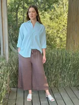 Camisa celeste a rayas verticales blancas, de corte holgado, manga larga y cuello camisero.