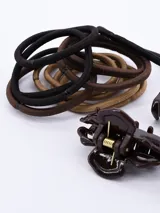 Set de accesorios para el cabello que incluye tres pinzas pequeñas de color marrón en diferentes tonos y ocho coleros elásticos en colores marrón y negro.