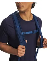 Mochila Under Armour de color azul marino, diseñada con tirantes acolchados y texturizados para mayor comodidad, correa ajustable en el pecho con hebilla y el logo de la marca en relieve.