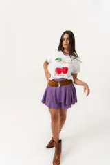 Remera blanca de algodón y elastano, con cuello redondo y mangas cortas. Estampado frontal con cerezas y texto en dorado.