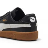 Championes Puma modelo Army Trainer, de diseño retro en color blanco con detalles en verde oscuro y suela de goma color caramelo. Presenta refuerzos de gamuza en la puntera y el logo de la marca en dorado en el lateral.