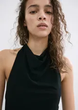 Vestido largo negro de corte slim, con cuello drapeado, sin mangas y detalle de fruncido lateral con caída de tela en la cadera.