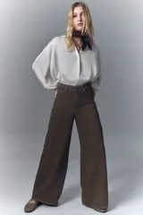 Jean de corte oxford y tiro alto, con pierna ancha desde la cadera hasta el ruedo. Confeccionado en denim rígido de color marrón, con cierre y botón frontal.