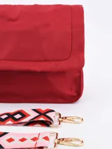 Bandolera roja de tela acolchada con solapa y cierre magnético. Incluye correa de hombro ajustable y extraíble, y detalle de borla de cordones de colores.