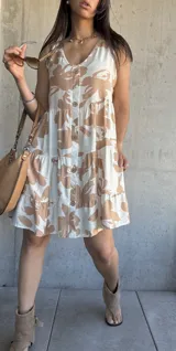 Vestido corto color beige con estampado de hojas marrones, escote en V, botones frontales y volados en ruedo.