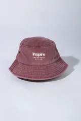 Gorro tipo bucket de gabardina color bordo, con efecto acid wash y bordado frontal en color blanco con el texto "Inspire GREATNESS by vcp".
