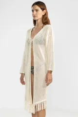 Cárdigan largo color crema de punto abierto con flecos en el ruedo y lazo de ajuste en el escote.