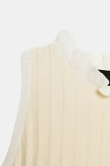 Top de punto color crema con cuello redondo y manga sisa. Presenta detalle de rib a contraste en el cuello y las sisas, y bajo acabado en peplum.