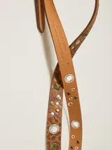 Cinto de cuero con estampado animal print de leopardo, decorado con tachas metálicas, remaches y ojales. Cuenta con una hebilla cuadrada de metal y una placa metálica con el logo de la marca.