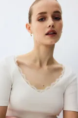 Top en punto acanalado fino de algodón, de color blanco, corte entallado, mangas cortas y escote en V pronunciado ribeteado con encaje.