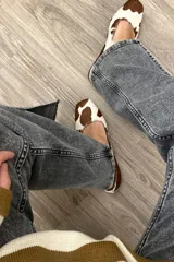 Zapato Mary Janes de cuero con estampado de vaca en tonos marrón y blanco, con correa sobre el empeine y hebilla metálica.