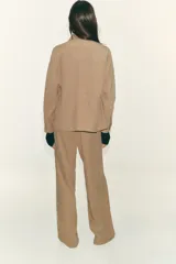 Chaqueta color tostado con cuello solapa, manga larga y cierre frontal con cremallera. Presenta bolsillos delanteros de plastrón con solapa y detalle de cintura ajustable con lazada.