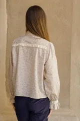 Camisa de algodón con estampado floral, cuello clásico, cierre frontal con botones, mangas largas con puños con volados y corte recto.