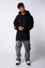 Buzo canguro oversize de tela friza, color negro, con capucha, cordones ajustables con logo y bolsillo frontal tipo canguro.