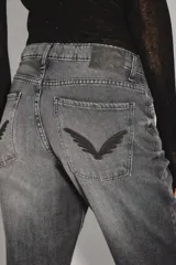 Jean de tiro alto con corte recto, confeccionado en denim rígido de color negro. Presenta un diseño clásico con cierre y botón, bolsillos traseros con bordado de alas y ruedo desarmado.